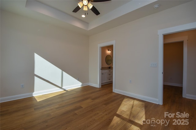 spare room featuring ceiling fan, dark hardwood / wood-style floors, and a raised ceiling