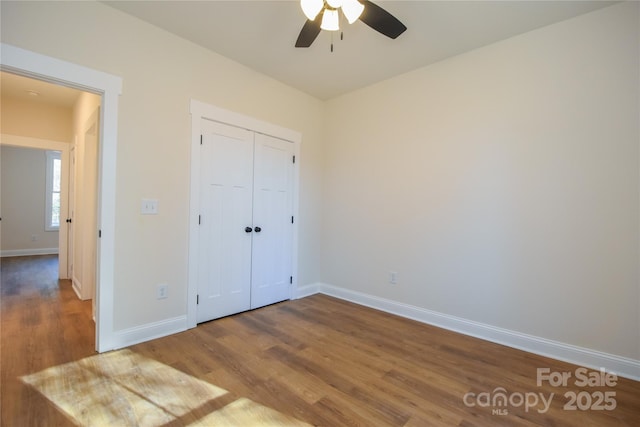 unfurnished bedroom with ceiling fan, a closet, and hardwood / wood-style flooring