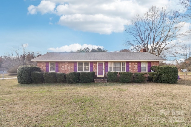 single story home with brick siding, a chimney, and a front lawn