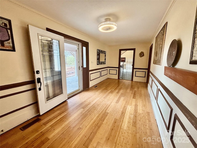 doorway with crown molding and light hardwood / wood-style flooring