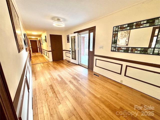 hall featuring ornamental molding and light hardwood / wood-style floors