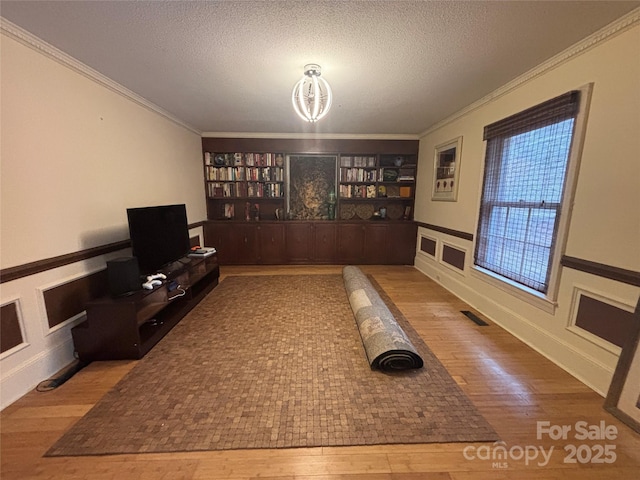 living room with hardwood / wood-style flooring, ornamental molding, and a textured ceiling