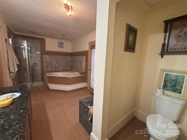 full bathroom with independent shower and bath, hardwood / wood-style flooring, vanity, toilet, and a textured ceiling