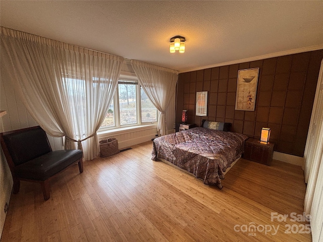 bedroom with ornamental molding, a textured ceiling, and light wood-type flooring