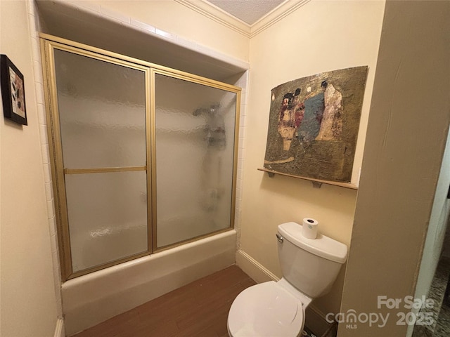 bathroom featuring hardwood / wood-style floors, crown molding, bath / shower combo with glass door, and toilet