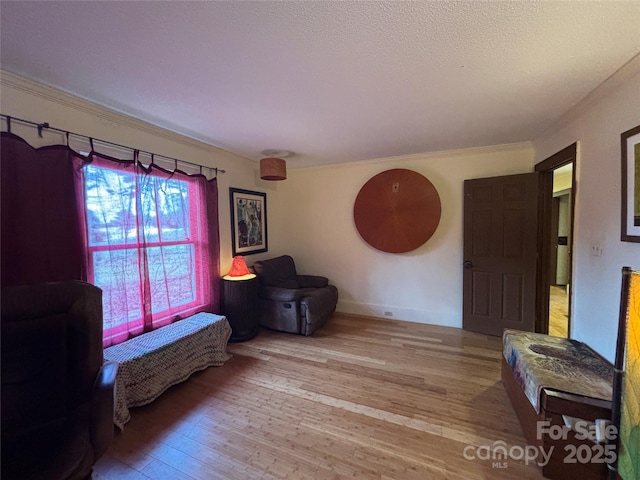 sitting room featuring crown molding, a textured ceiling, and light hardwood / wood-style flooring