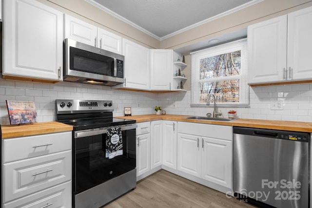 kitchen featuring white cabinetry, sink, butcher block countertops, and appliances with stainless steel finishes