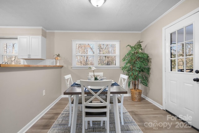 dining area with light hardwood / wood-style floors, ornamental molding, and a healthy amount of sunlight