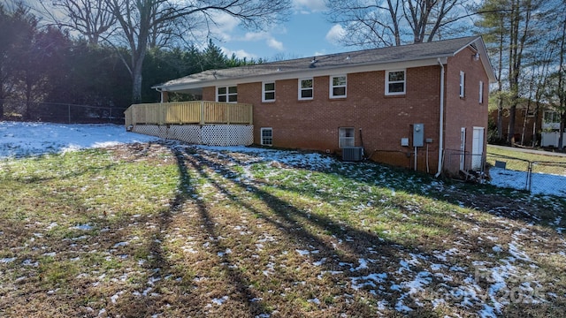 snow covered property with a wooden deck, central air condition unit, and a yard