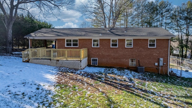 snow covered house with central AC unit and a deck