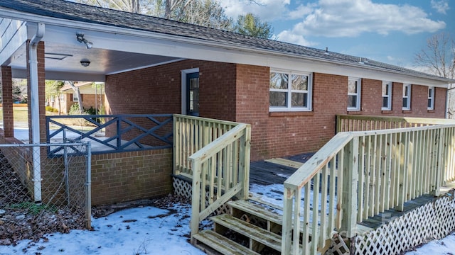 snow covered back of property with a wooden deck