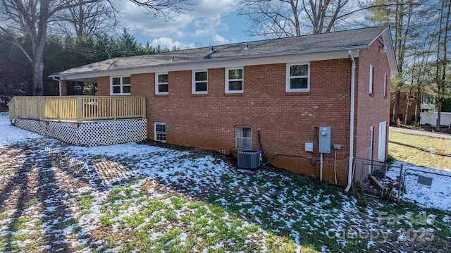 snow covered back of property featuring a wooden deck and central air condition unit