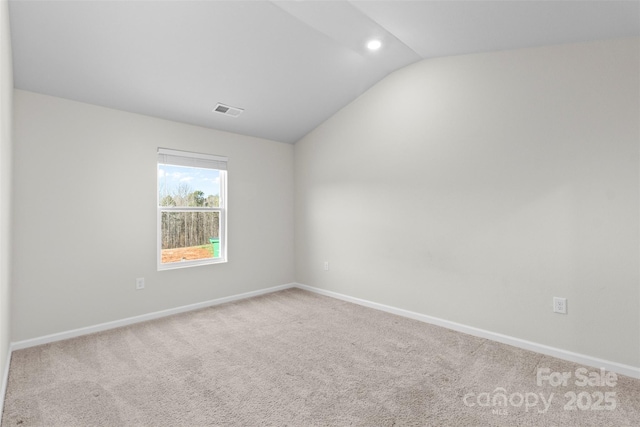 carpeted spare room with vaulted ceiling