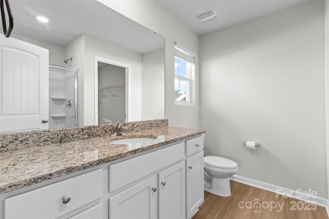 bathroom featuring vanity, a shower with shower door, hardwood / wood-style floors, and toilet