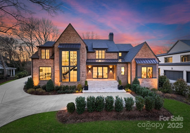 view of front of home featuring a standing seam roof, brick siding, metal roof, and a chimney