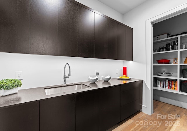 kitchen featuring light countertops, modern cabinets, a sink, and light wood-style flooring