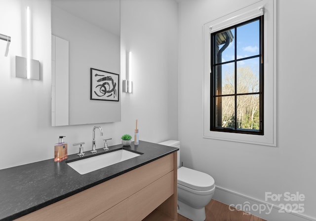 bathroom with toilet, baseboards, and vanity