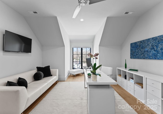 living room with light wood-type flooring, visible vents, and vaulted ceiling