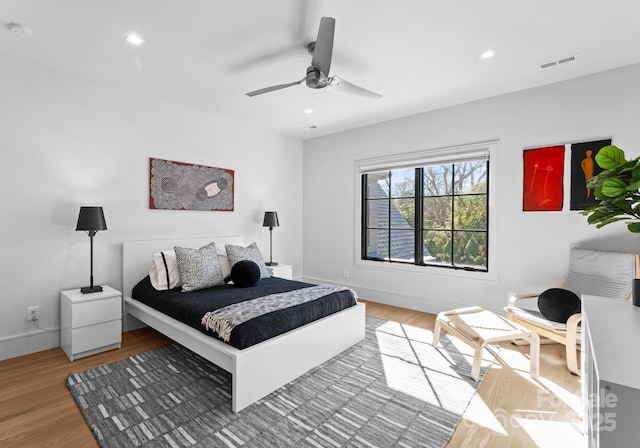 bedroom with baseboards, visible vents, ceiling fan, and wood finished floors