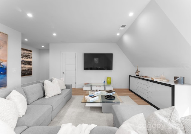 living room featuring recessed lighting, visible vents, light wood-style flooring, vaulted ceiling, and baseboards