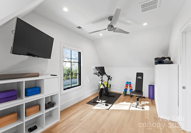 workout area with light wood-style floors, visible vents, vaulted ceiling, and baseboards