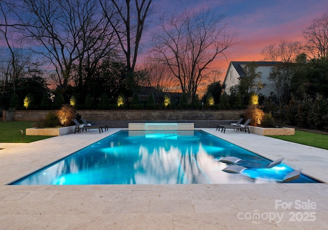 pool at dusk featuring a patio area and an outdoor pool