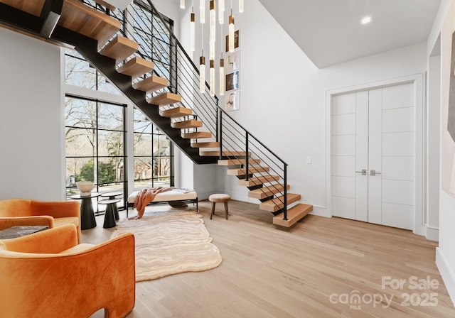 interior space featuring light wood finished floors, a high ceiling, stairway, and a wealth of natural light