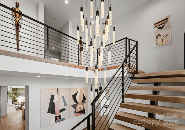 stairway featuring wood finished floors and a towering ceiling