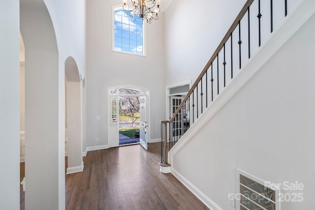 entryway featuring dark wood-type flooring, a chandelier, and a high ceiling