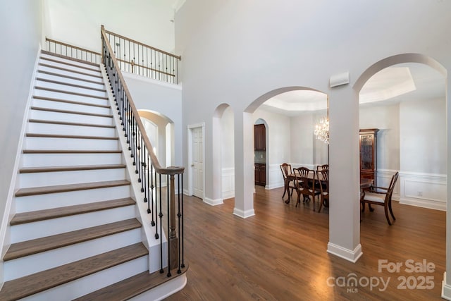 staircase with an inviting chandelier, hardwood / wood-style floors, and a tray ceiling