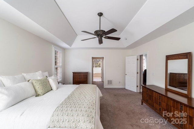 carpeted bedroom featuring ceiling fan and a raised ceiling