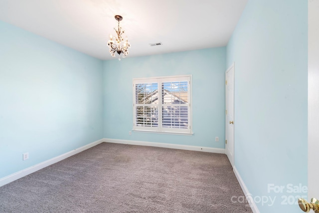 spare room featuring carpet floors and a notable chandelier