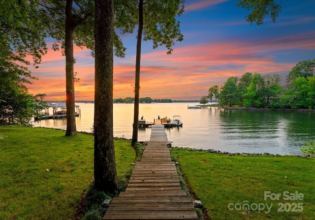 view of dock with a water view and a yard