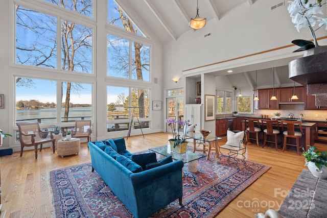 living room with a water view, light hardwood / wood-style flooring, and high vaulted ceiling