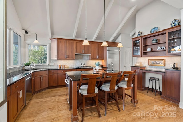 kitchen with a breakfast bar area, decorative light fixtures, high vaulted ceiling, a kitchen island, and sink