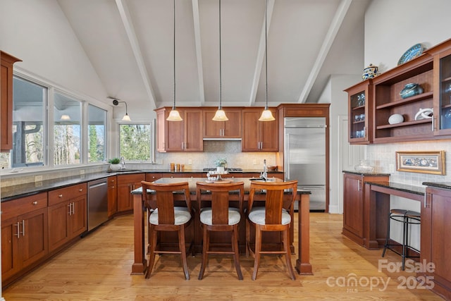 kitchen featuring decorative light fixtures, a kitchen bar, appliances with stainless steel finishes, and dark stone countertops