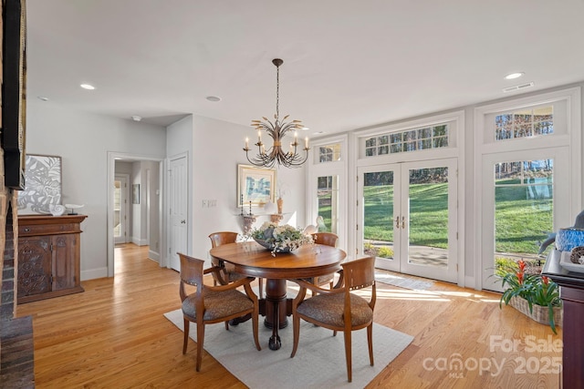 dining room featuring french doors, an inviting chandelier, and light hardwood / wood-style floors