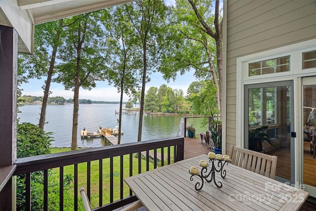 wooden terrace with a water view, a lawn, and a boat dock