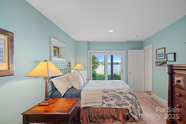 carpeted bedroom with access to exterior and a water view