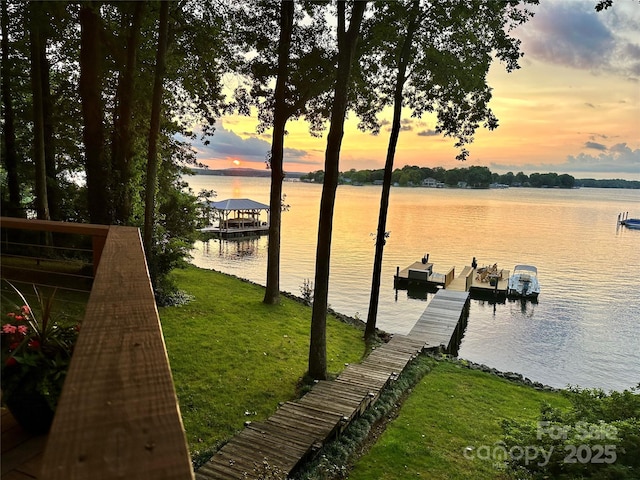 view of dock featuring a lawn and a water view