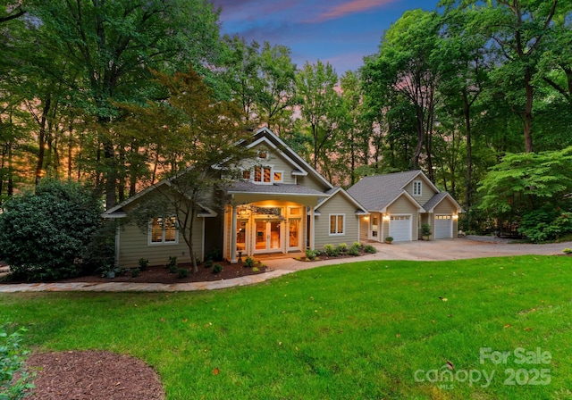 view of front of house with a garage, french doors, and a lawn