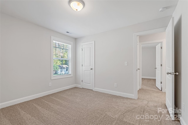 unfurnished bedroom with light carpet and a closet