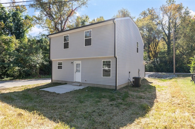 rear view of property with central AC unit and a yard