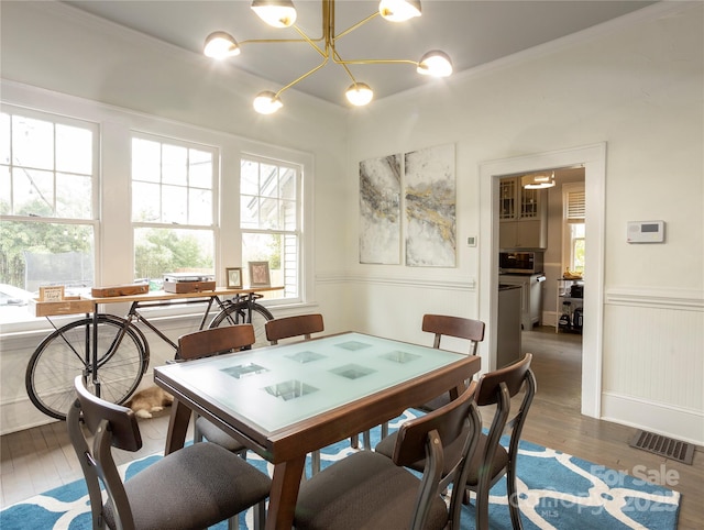 dining area featuring dark hardwood / wood-style flooring, ornamental molding, and a chandelier