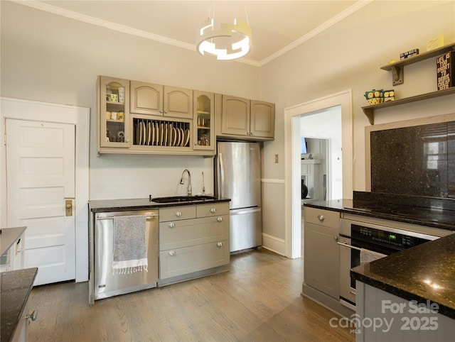 kitchen featuring appliances with stainless steel finishes, hardwood / wood-style floors, sink, backsplash, and hanging light fixtures