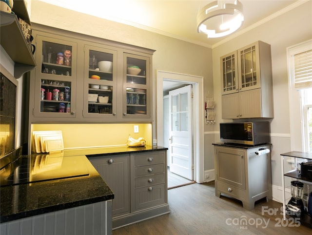 kitchen with dark hardwood / wood-style floors, gray cabinetry, dark stone counters, crown molding, and black electric cooktop