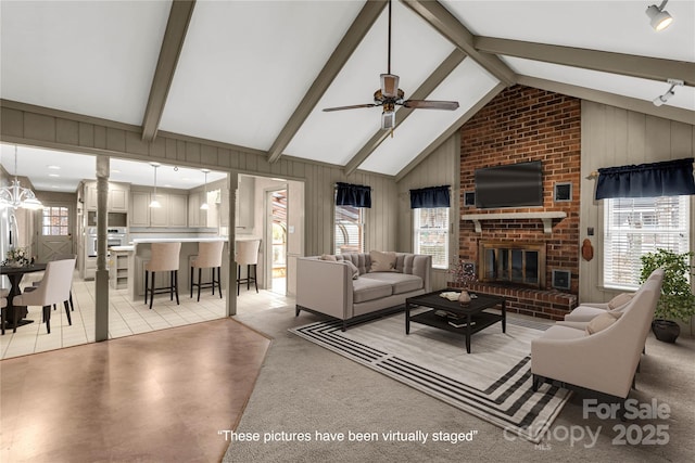 living room featuring beamed ceiling, wooden walls, a fireplace, and a wealth of natural light