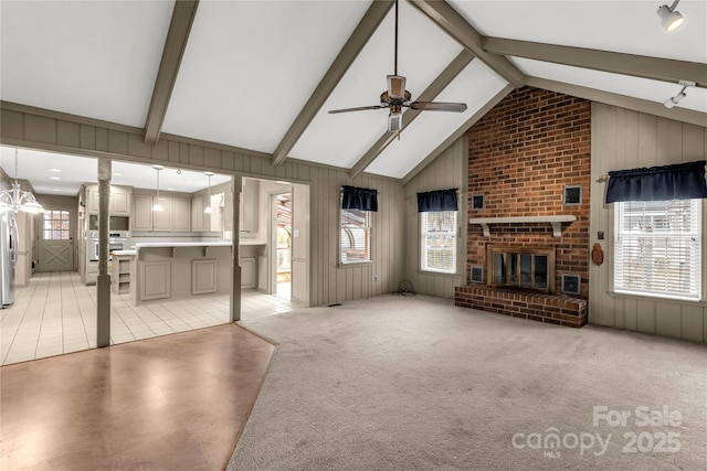 unfurnished living room featuring beam ceiling, ceiling fan, light colored carpet, and a fireplace