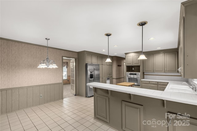 kitchen with pendant lighting, sink, stainless steel appliances, and kitchen peninsula