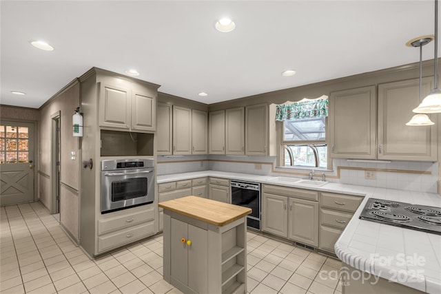 kitchen featuring pendant lighting, sink, gray cabinetry, a center island, and black appliances